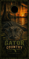 A rectangular cornhole board with a Florida gator swamp scene, featuring a large alligator head, trees, water, and sunset glow. The text 'GATOR COUNTRY' and 'FLORIDA' are printed on the board, with a circular hole near the top center.